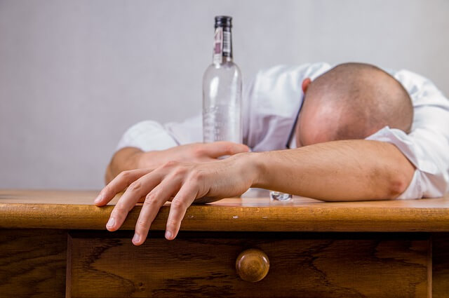 Śpiący człowiek z butelką po alkoholu