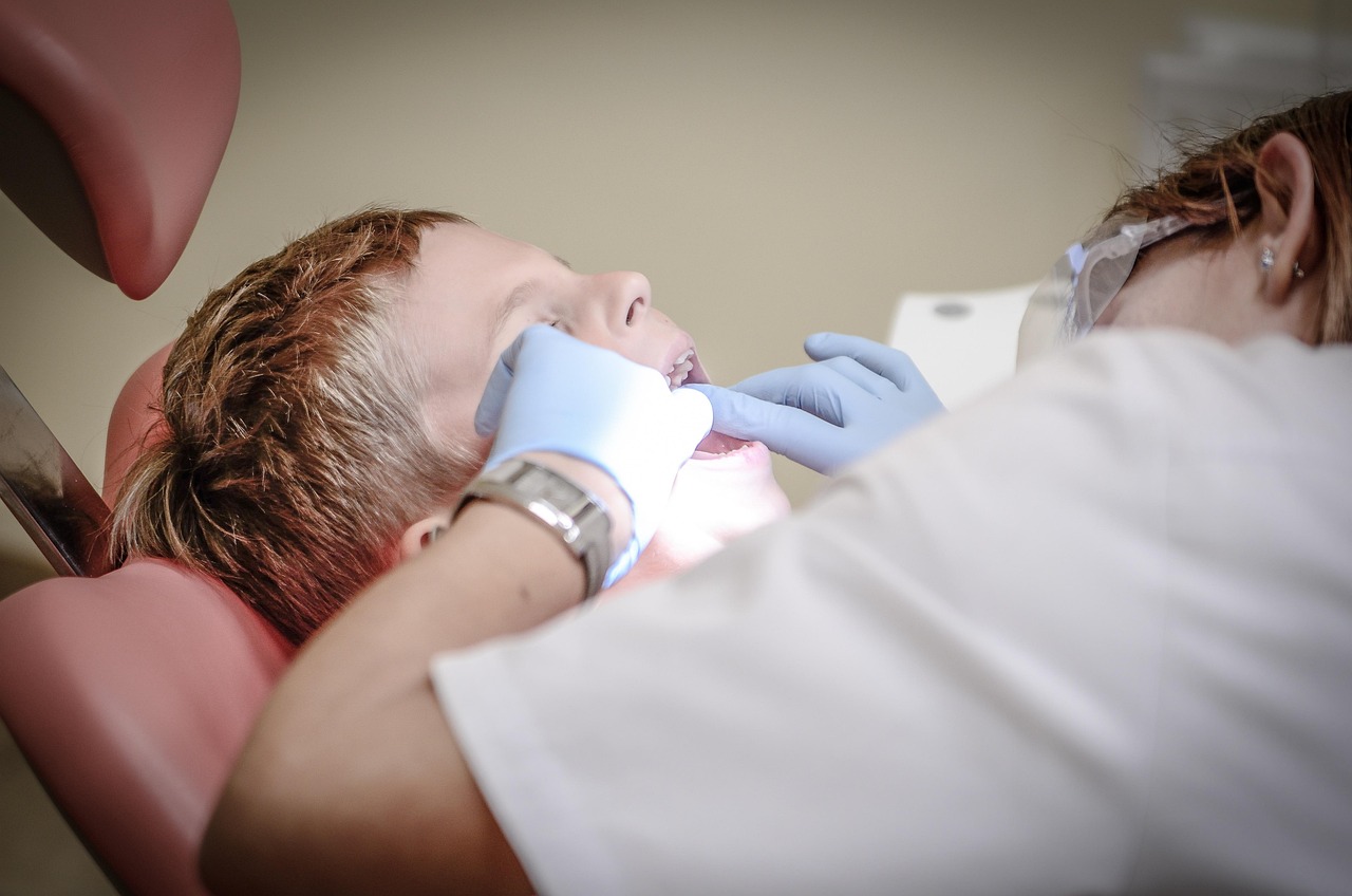 Dziecko podczas badania zębów przez dentystkę w fotelu stomatologicznym